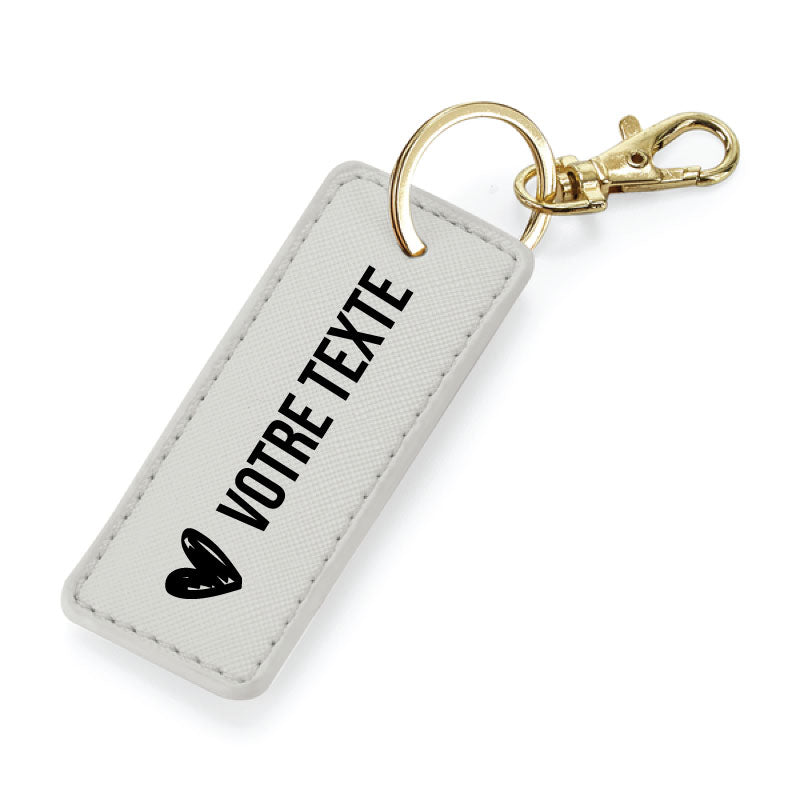 Porte-clés gris en simili cuir avec anneau métallique or, finition élégante et message personnalisable.